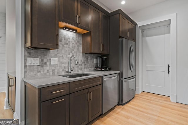 kitchen featuring a sink, stainless steel appliances, light countertops, dark brown cabinets, and light wood-style floors