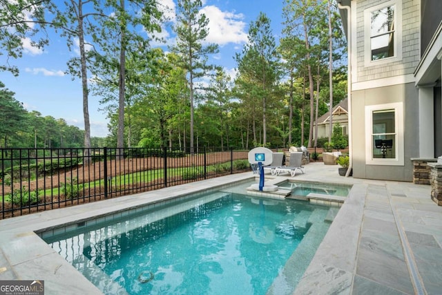 view of swimming pool featuring a patio area, a pool with connected hot tub, and fence