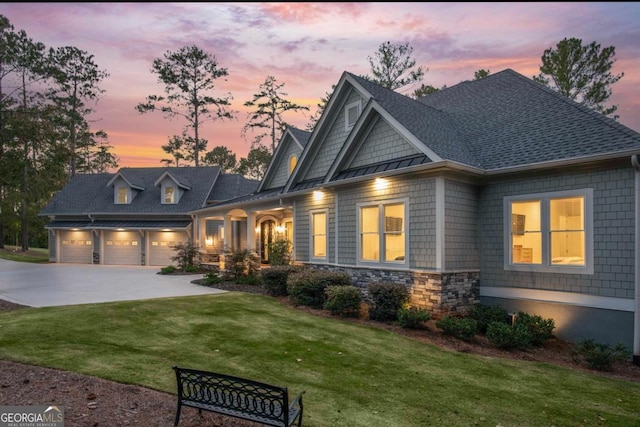 craftsman-style home featuring driveway, stone siding, a front yard, a shingled roof, and a garage