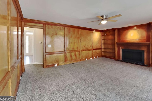 unfurnished living room featuring light carpet, a ceiling fan, a fireplace with flush hearth, and crown molding