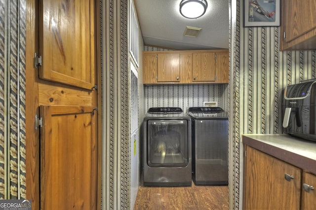 laundry room featuring visible vents, wood finished floors, cabinet space, a textured ceiling, and independent washer and dryer