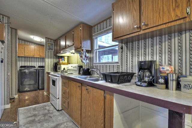 kitchen featuring wallpapered walls, electric range, separate washer and dryer, a sink, and under cabinet range hood