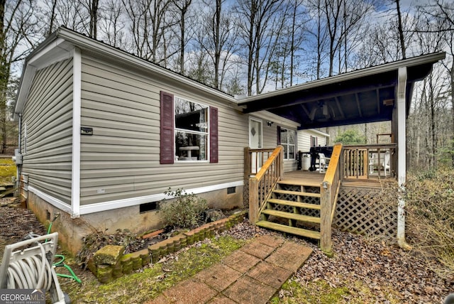 view of side of home with crawl space and a deck