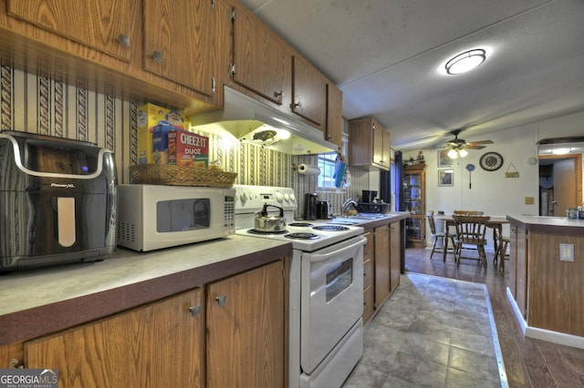 kitchen featuring ceiling fan, under cabinet range hood, brown cabinets, white appliances, and a sink