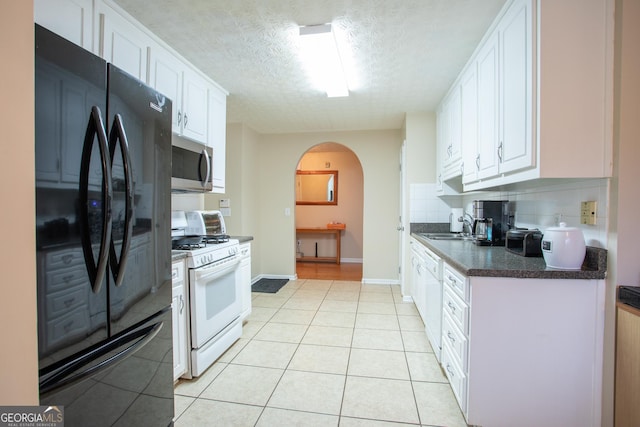 kitchen with dark countertops, backsplash, arched walkways, white appliances, and white cabinetry