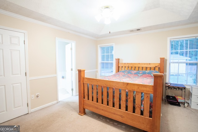 carpeted bedroom featuring a tray ceiling, baseboards, visible vents, and ornamental molding