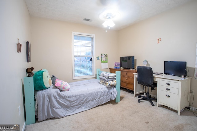 bedroom featuring a textured ceiling, visible vents, and light carpet