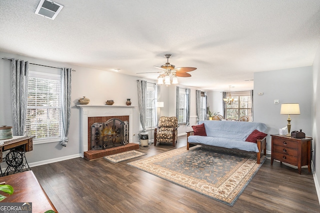 living area featuring baseboards, visible vents, dark wood-type flooring, a textured ceiling, and a brick fireplace