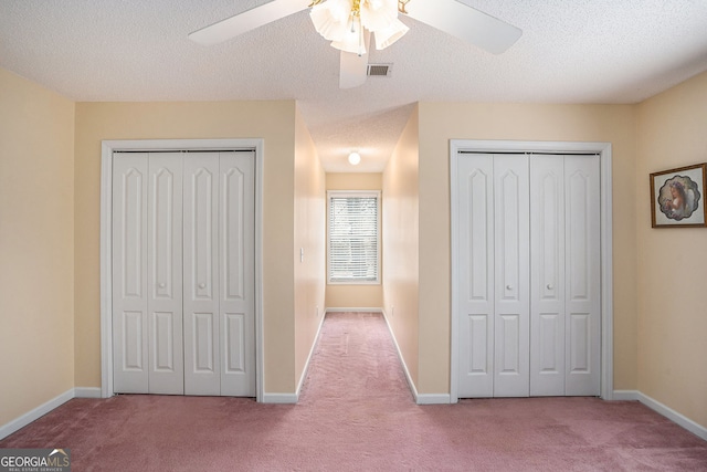 unfurnished bedroom featuring visible vents, carpet floors, two closets, and baseboards