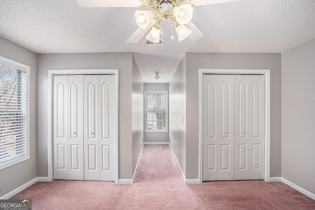 unfurnished bedroom featuring baseboards, visible vents, two closets, and carpet floors