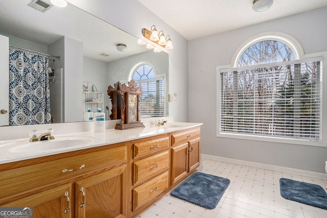 bathroom featuring a sink, visible vents, double vanity, and tile patterned floors