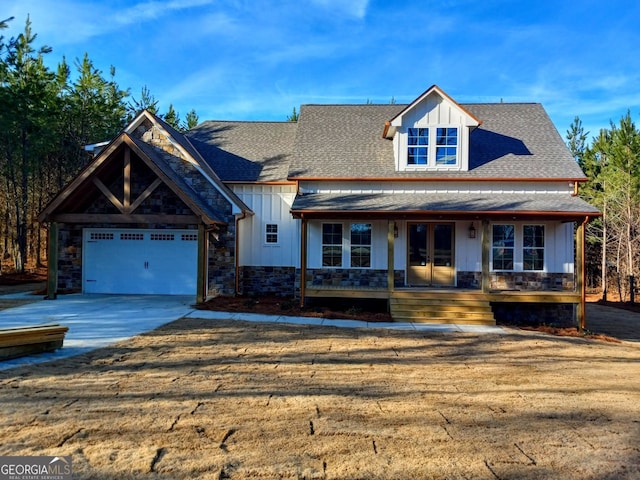 view of front of property featuring driveway, stone siding, french doors, roof with shingles, and board and batten siding