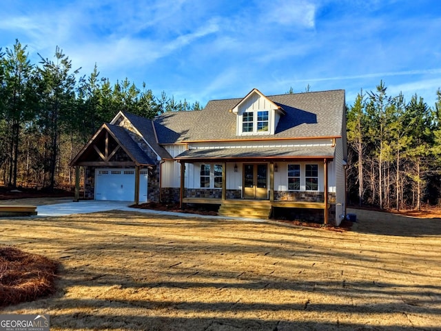 view of front of house with a porch, a garage, french doors, and stone siding