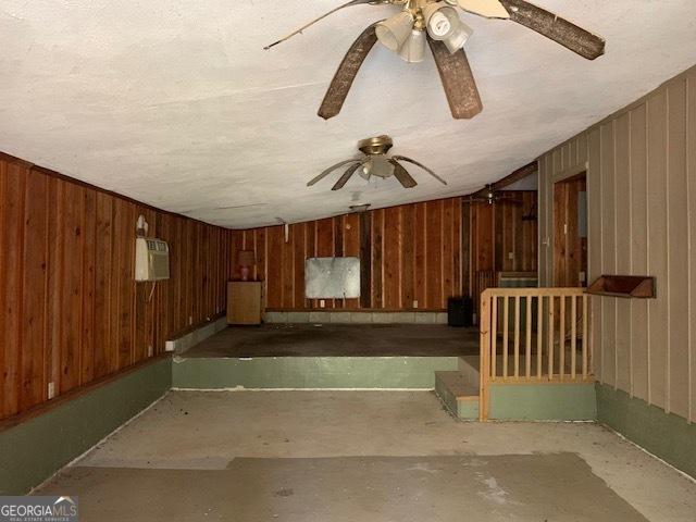 interior space with wood walls and ceiling fan