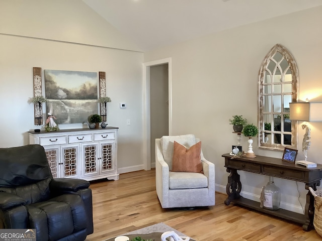 living area with wood finished floors, baseboards, and vaulted ceiling