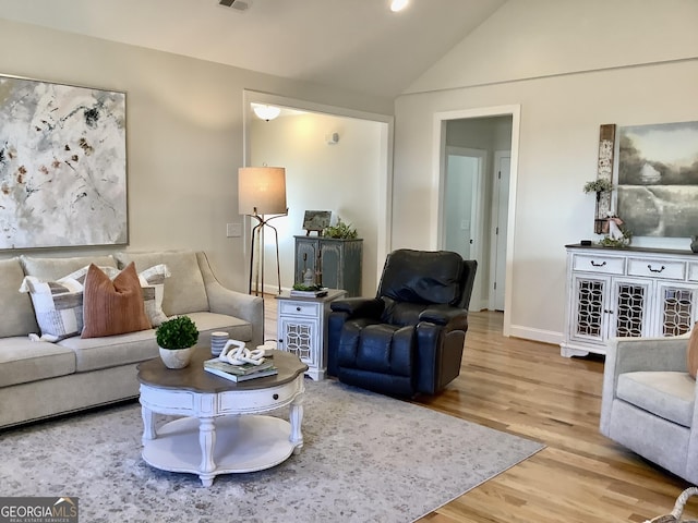 living room featuring visible vents, wood finished floors, baseboards, and vaulted ceiling