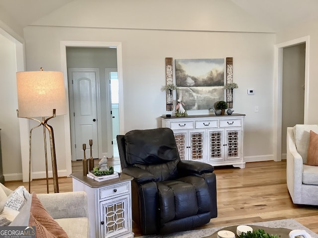 living room featuring baseboards, lofted ceiling, and light wood-style flooring