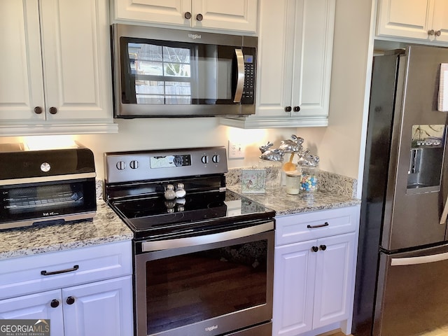 kitchen with white cabinets, a toaster, light stone countertops, and stainless steel appliances