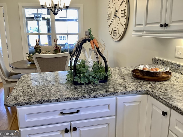 kitchen with white cabinets, dark stone counters, and an inviting chandelier