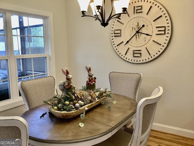 dining room with a notable chandelier, wood finished floors, and baseboards