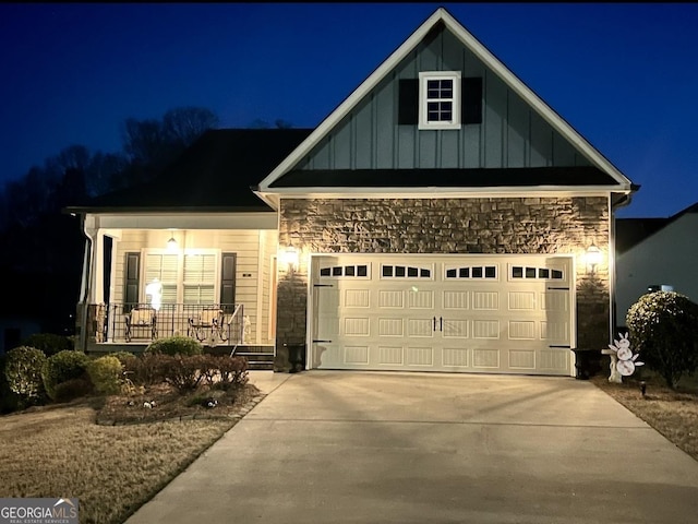 view of front of home with driveway, a porch, a garage, stone siding, and board and batten siding