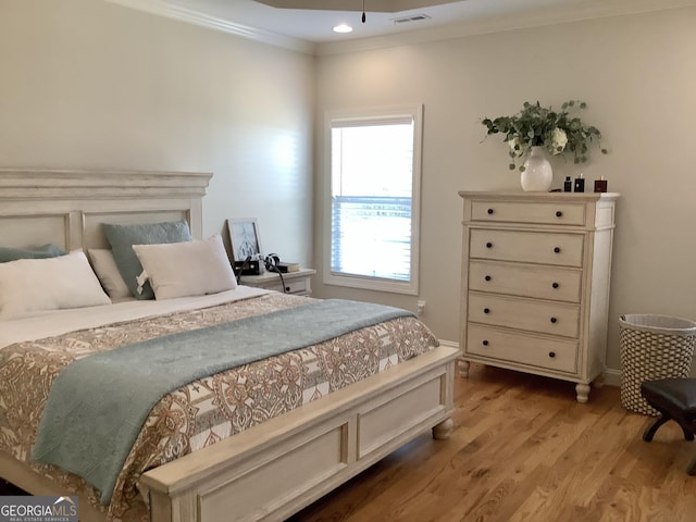 bedroom featuring crown molding, light wood-style flooring, and visible vents