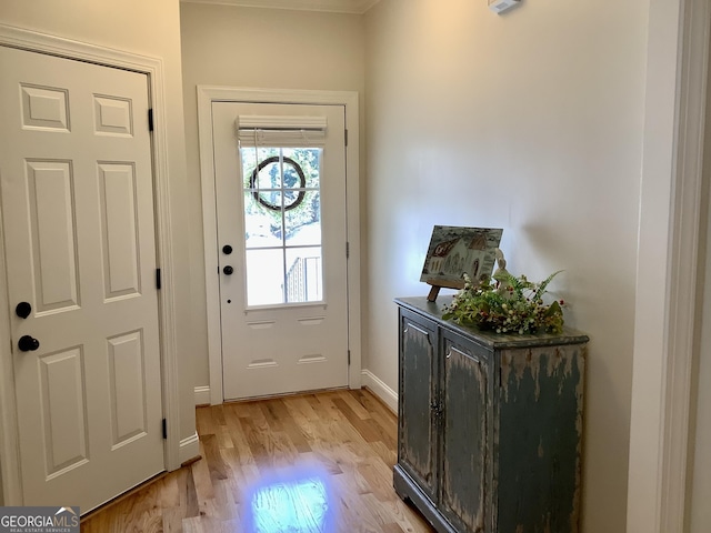 doorway to outside featuring baseboards and light wood-style floors