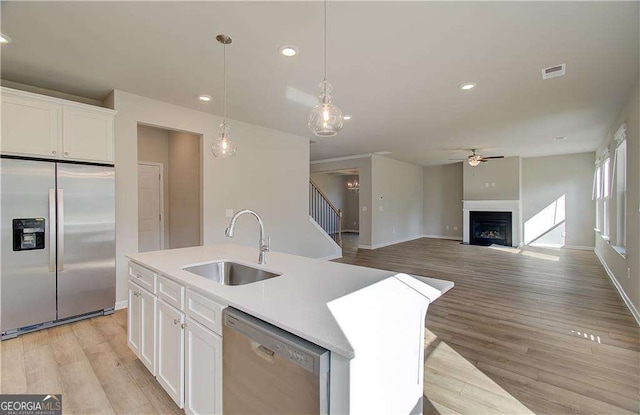 kitchen with visible vents, appliances with stainless steel finishes, a fireplace, white cabinets, and a sink