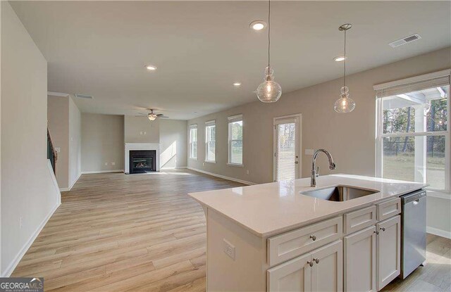 kitchen featuring visible vents, light wood-style flooring, a fireplace, a sink, and dishwasher