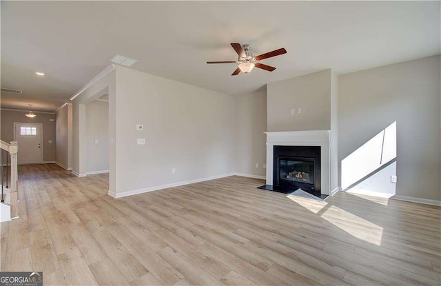 unfurnished living room featuring a ceiling fan, a fireplace with flush hearth, baseboards, and light wood-type flooring