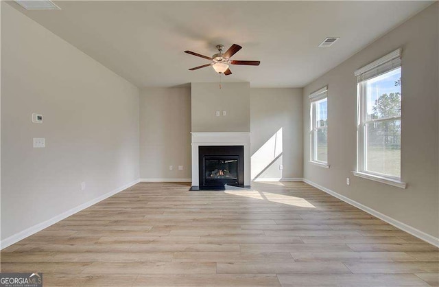 unfurnished living room featuring visible vents, a fireplace with flush hearth, baseboards, and light wood-style flooring