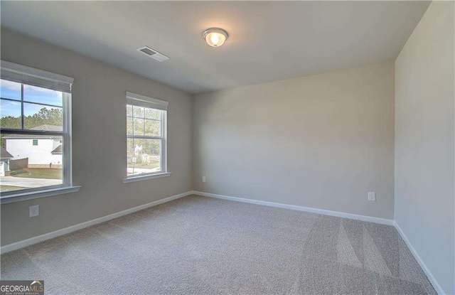 carpeted empty room featuring visible vents and baseboards