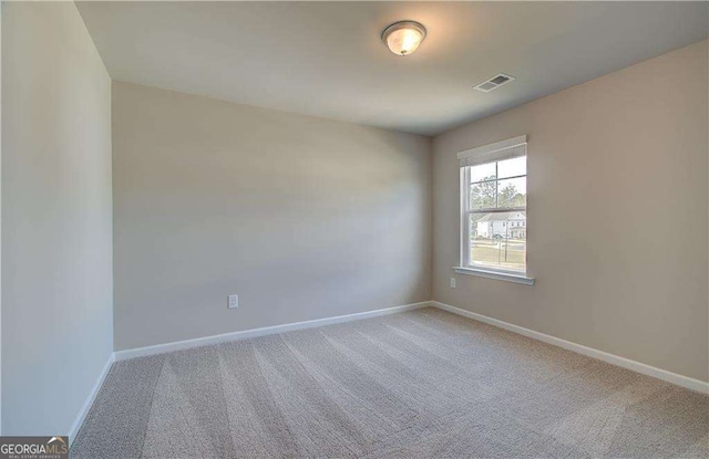 carpeted empty room featuring baseboards and visible vents