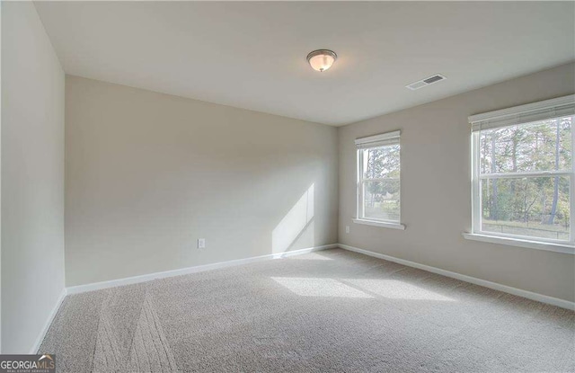 unfurnished room with light carpet, visible vents, and baseboards