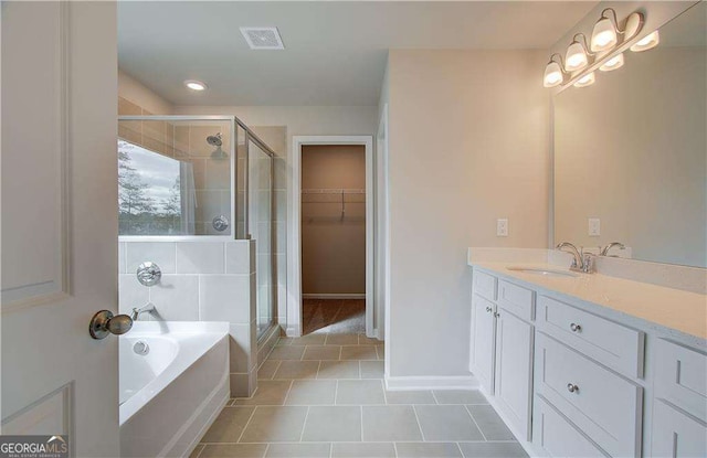 bathroom featuring vanity, visible vents, a stall shower, a spacious closet, and a bath