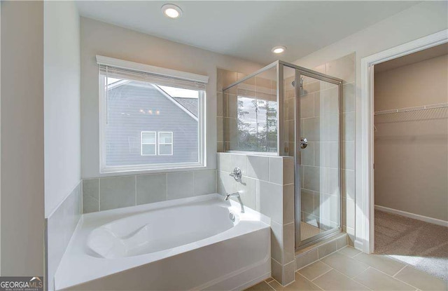 bathroom featuring a walk in closet, a shower stall, a garden tub, and recessed lighting