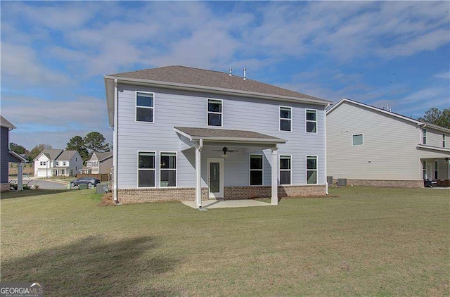 back of house with brick siding, a lawn, a patio, and a ceiling fan