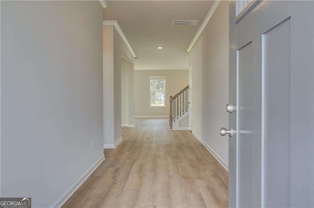 corridor featuring visible vents, baseboards, stairs, light wood-style floors, and crown molding