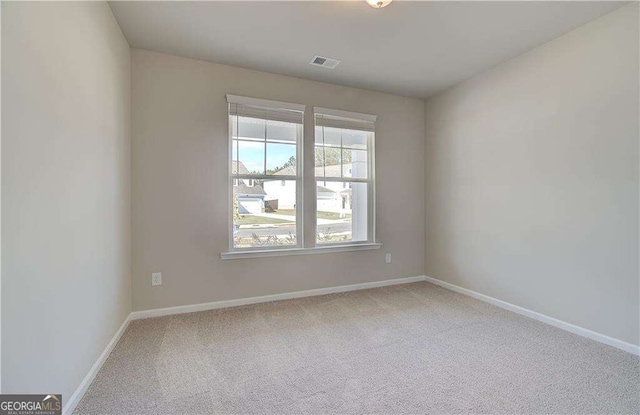 carpeted spare room with visible vents and baseboards