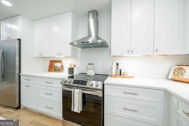 kitchen featuring white cabinetry, wall chimney exhaust hood, tasteful backsplash, and appliances with stainless steel finishes