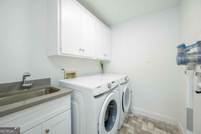 clothes washing area featuring baseboards, cabinet space, separate washer and dryer, a sink, and stone finish flooring