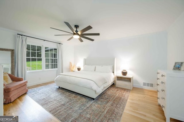 bedroom featuring visible vents, baseboards, crown molding, and light wood finished floors