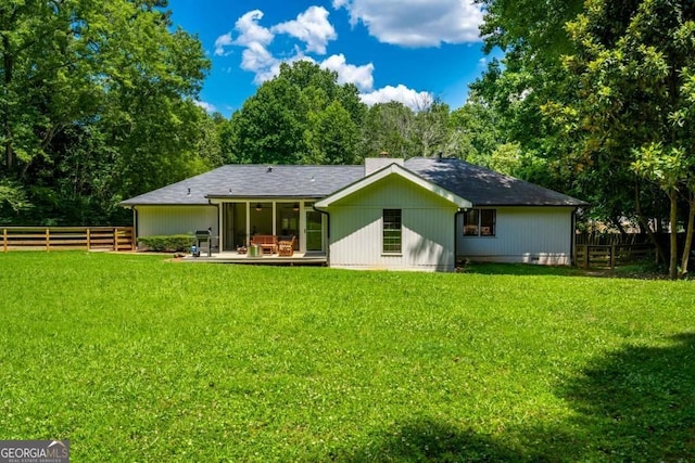 back of property with a lawn and fence