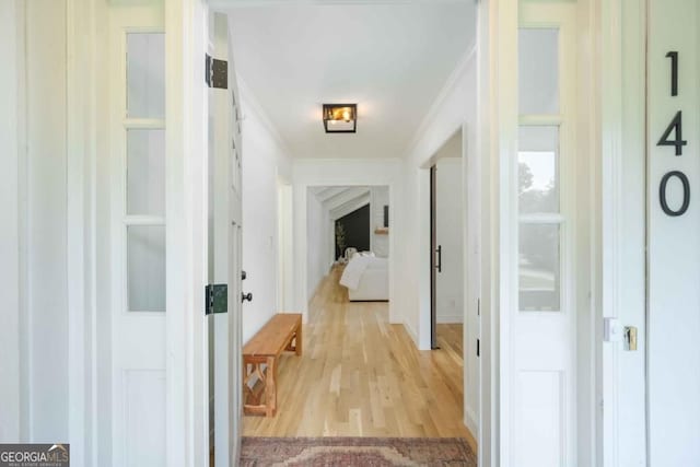 hallway with light wood-type flooring and ornamental molding