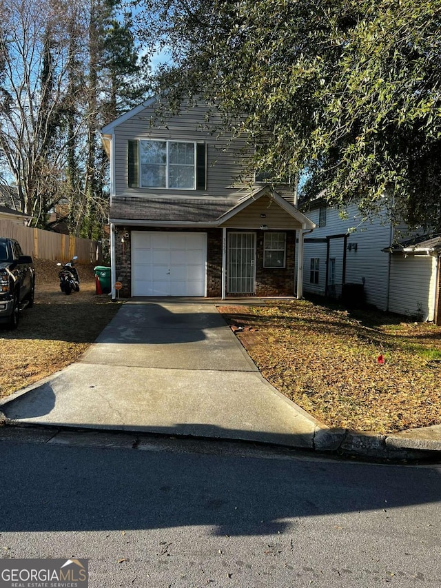 traditional home with brick siding, an attached garage, driveway, and fence