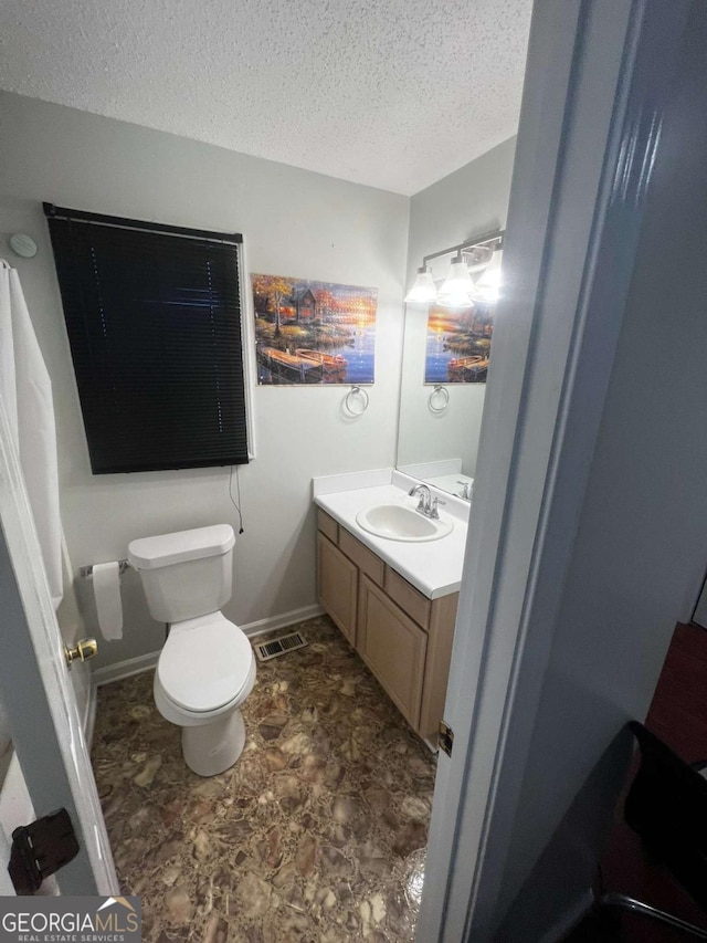 bathroom featuring visible vents, toilet, a textured ceiling, baseboards, and vanity