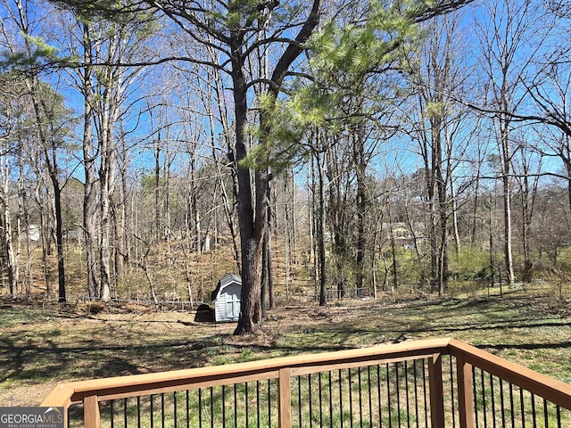 deck featuring a storage unit, an outbuilding, and a wooded view