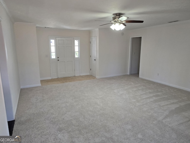 carpeted foyer featuring visible vents, baseboards, and crown molding