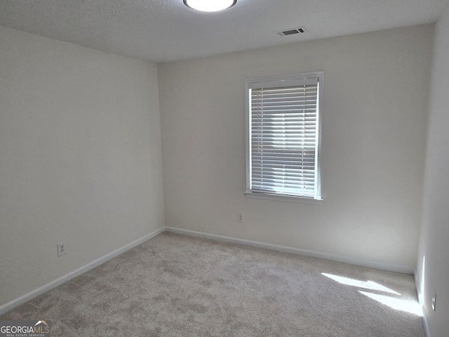 carpeted spare room with visible vents and baseboards