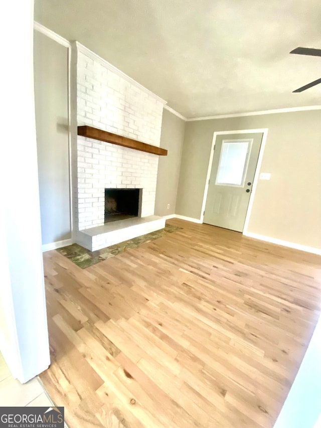 unfurnished living room with light wood-style flooring, a fireplace, baseboards, and ornamental molding